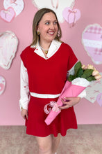 Load image into Gallery viewer, Woman in a red skirt set holding flowers against a pink background with heart decorations

