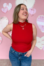 Load image into Gallery viewer, Woman wearing a red sleeveless top and blue jeans against a pink background with heart decorations.
