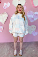 Load image into Gallery viewer, Woman wearing a pastel quilted outfit in front of a pink wall with heart decorations.
