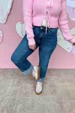 Load image into Gallery viewer, Person wearing a pink sweater and blue jeans against a pink wall with leg up.
