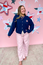 Load image into Gallery viewer, Woman wearing a navy blue cardigan and pink polka dot pants standing in front of a pink wall with star decorations.
