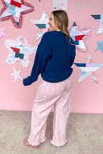 Load image into Gallery viewer, Woman wearing a blue sweater and pink polka dot pants standing in front of a star-patterned wall.
