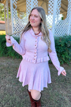 Load image into Gallery viewer, Girl wearing a pink ruffle cardigan skirt set with brown knee high boots standing in front of a gazebo. 
